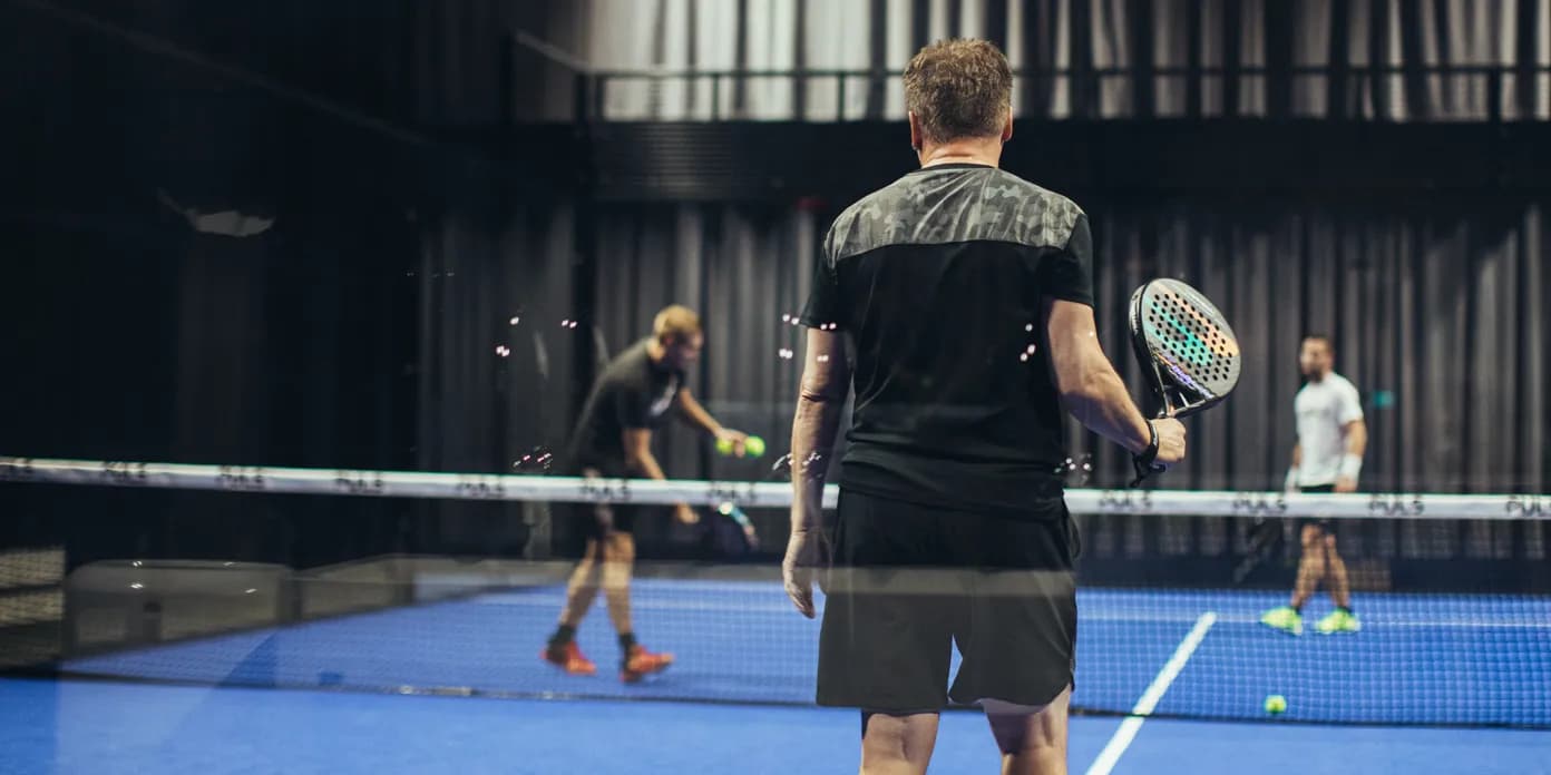 En man som står på en padelbana.