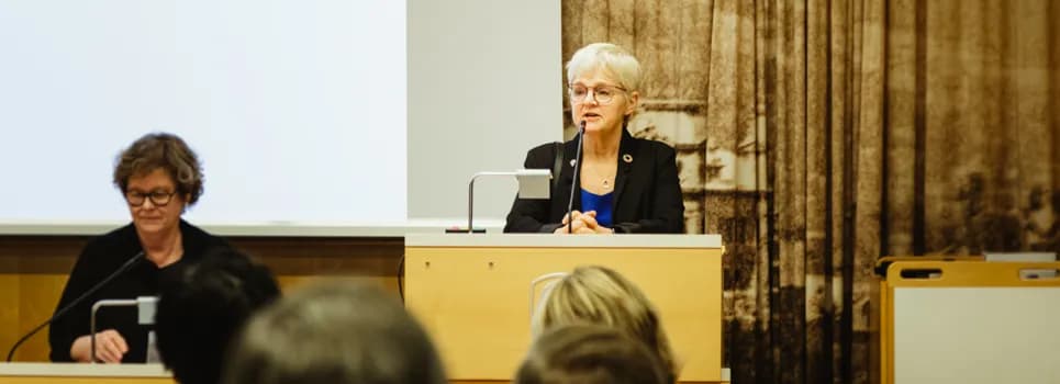 En kvinna står på ett podium framför en folkmassa.
