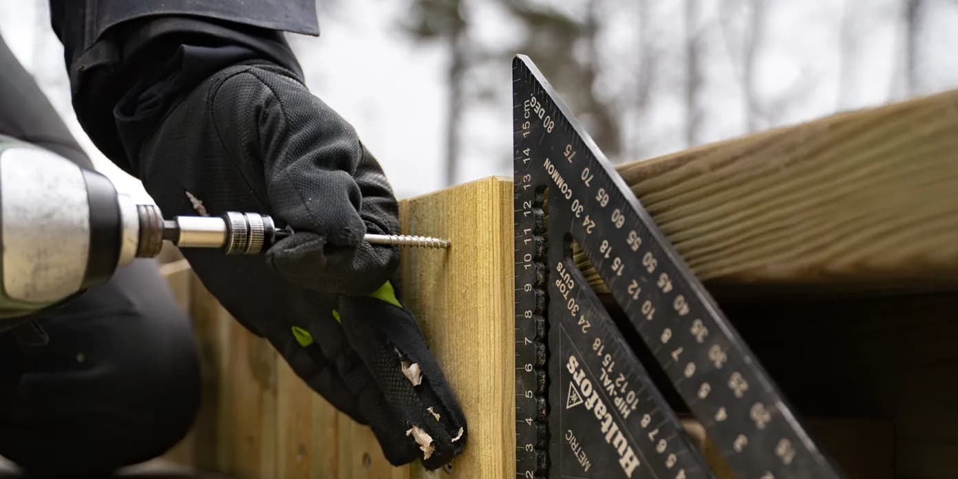 En person som använder en borrmaskin för att kapa en träbit