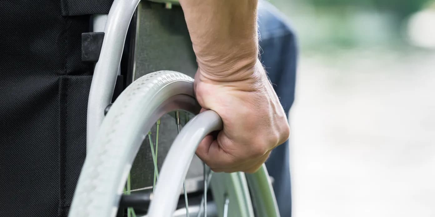 Närbild på en hand på ett rullstolshjul