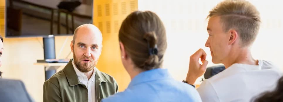 Bild på tre personer som sitter och pratar med varandra.