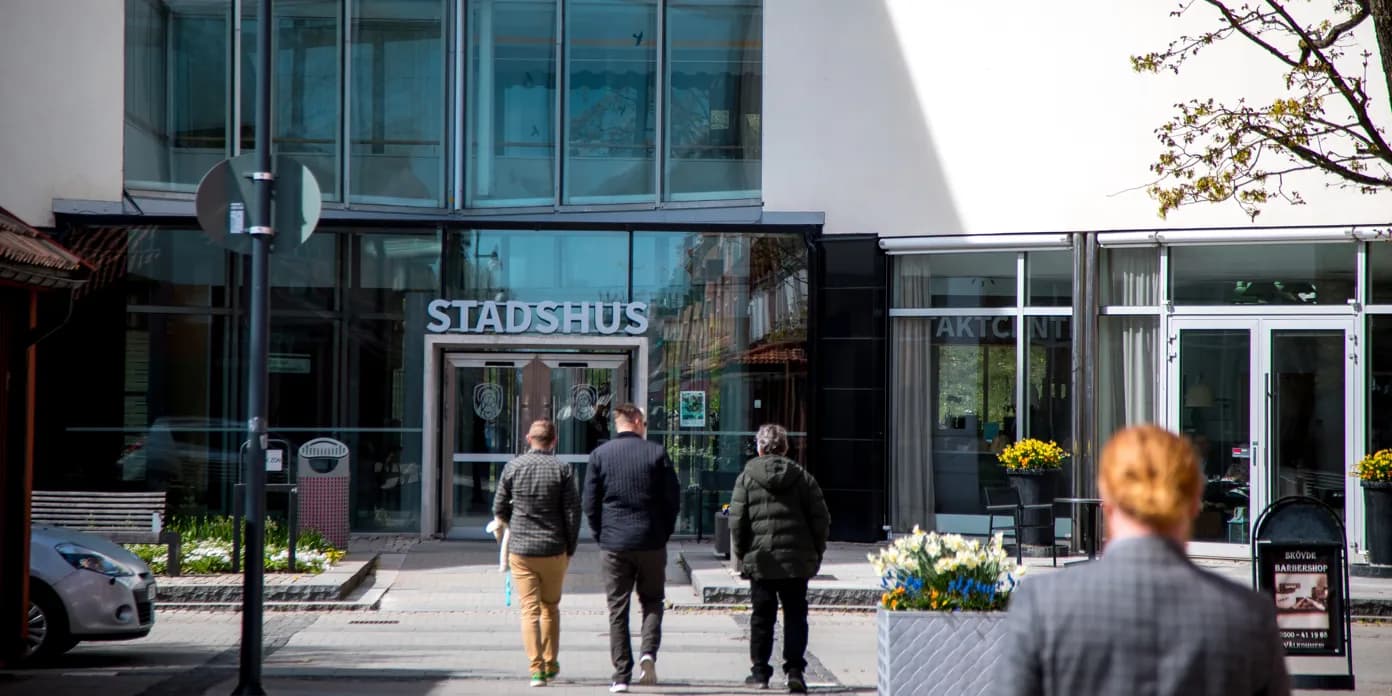 En grupp människor som går framför Skövdes stadshus