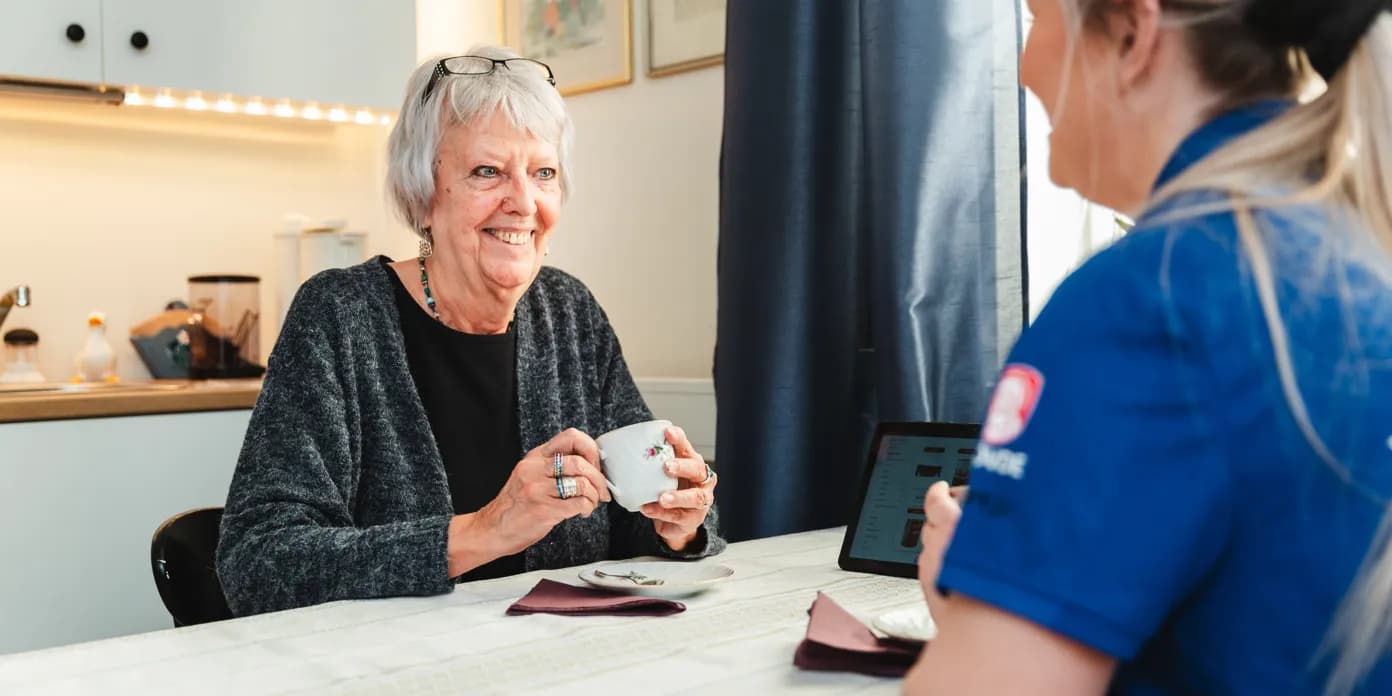 En kvinna sitter vid ett bord med en kopp kaffe