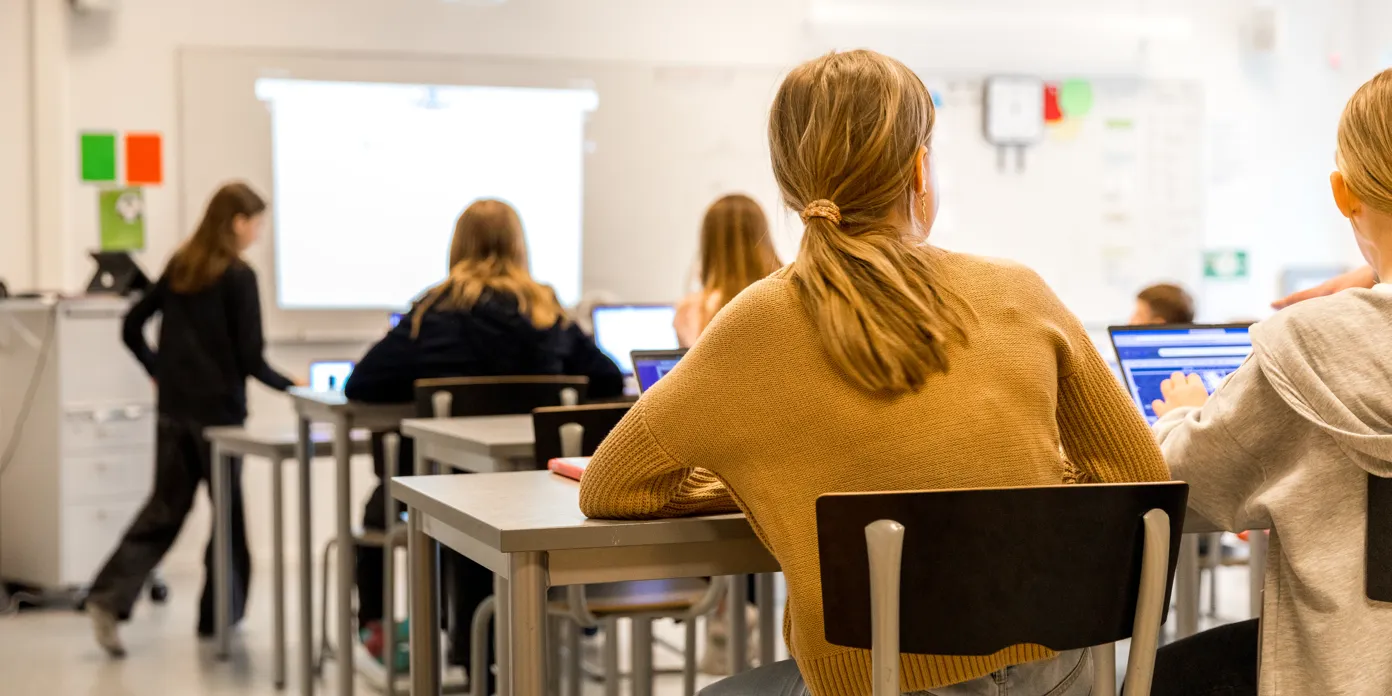 En grupp ungdomar som sitter vid bänkar i ett klassrum.